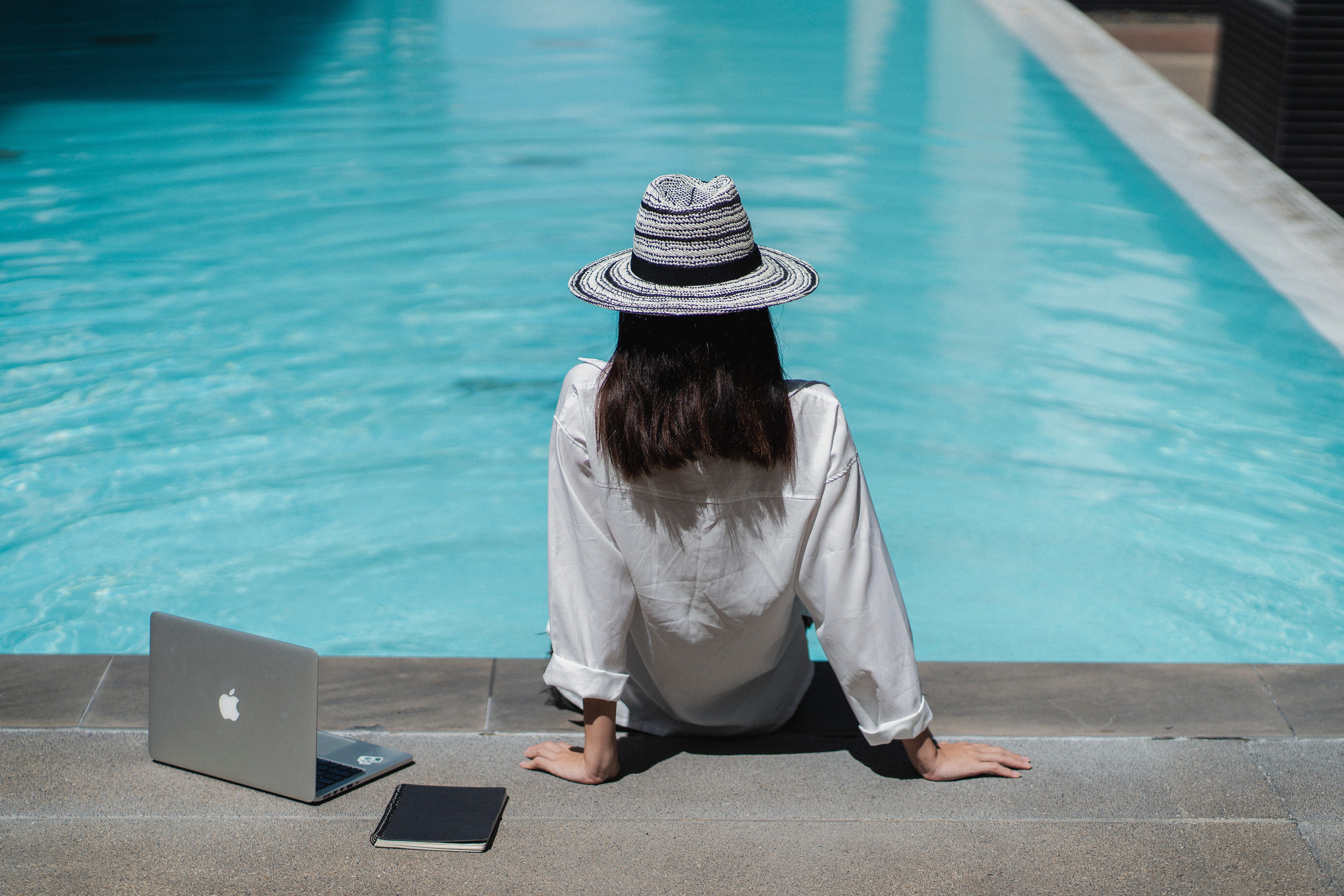 lady sitting besides a poll with a laptop open